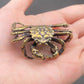 Brass mitten crab figurine resting in an open palm, showing its palm-sized scale and detailed legs