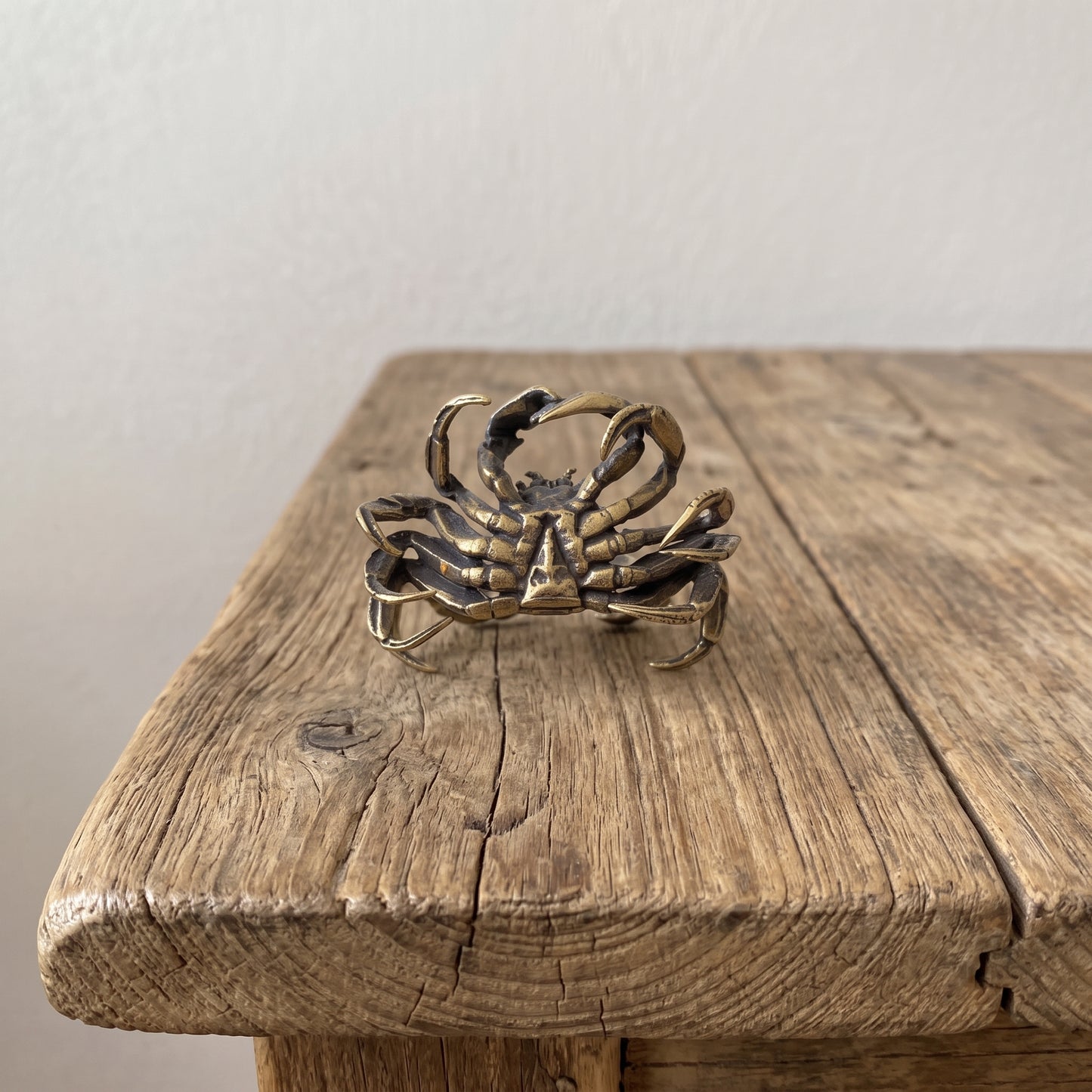 Front view of a brass mitten crab figurine with both claws raised, showing articulated legs and antique patina