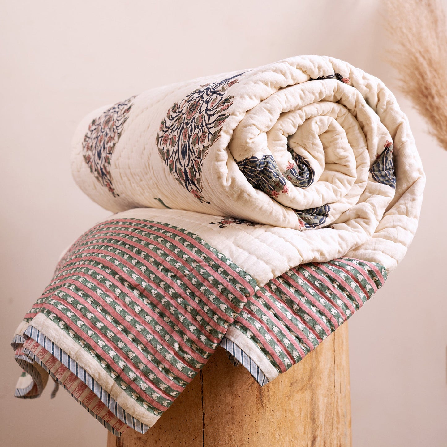 Royal umbrella hand block-printed quilt from Jaipur India, rolled on bed, showing cream cotton with umbrella motif, from WILLAGE