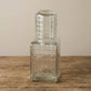 Multiple ruffle glass carafes with tumbler lids showing light catching the ribbed texture from different angles