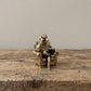 The Scholar brass reading dog figurine held in a hand to show its small size, about 1.8 inches tall