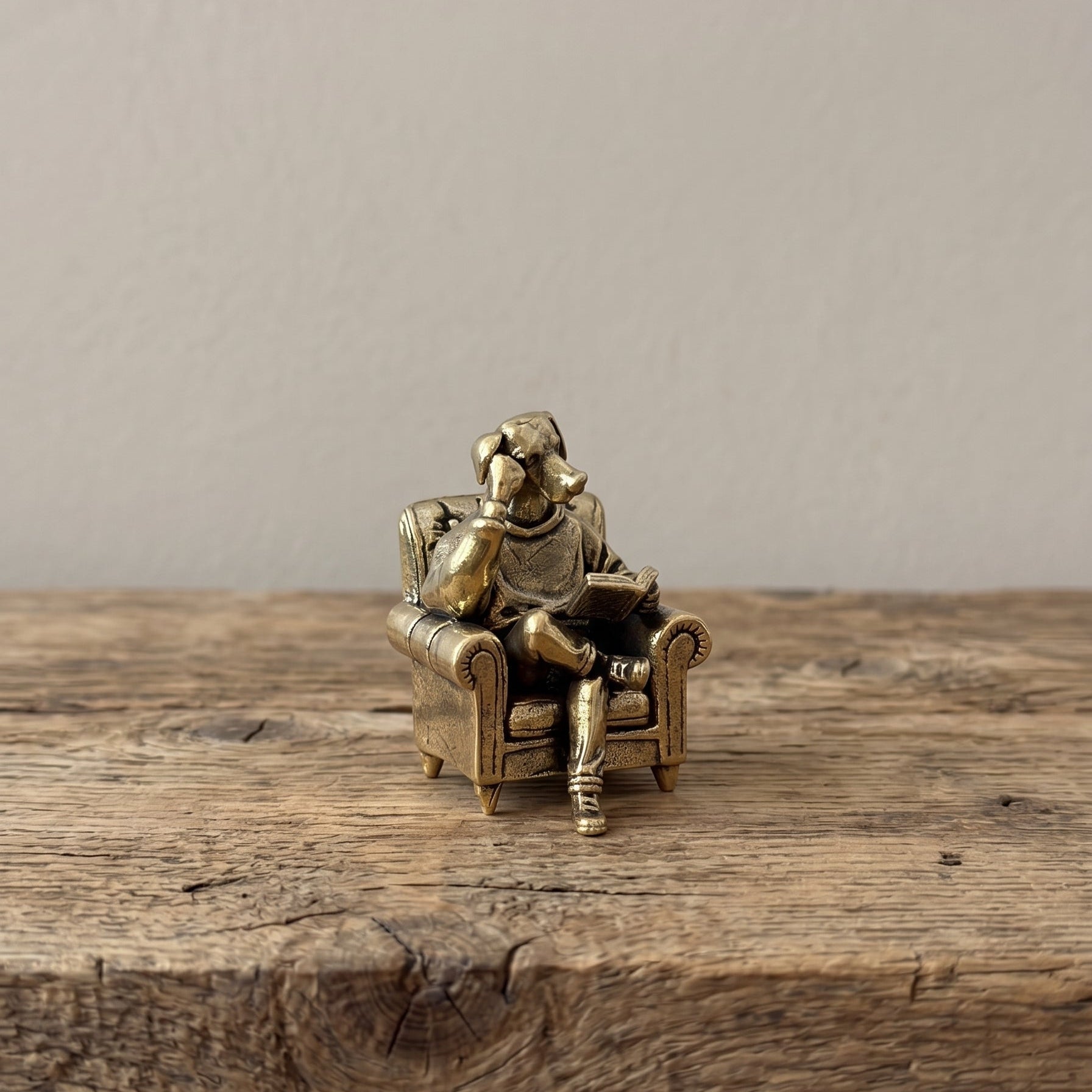 The Scholar brass reading dog figurine held in a hand to show its small size, about 1.8 inches tall
