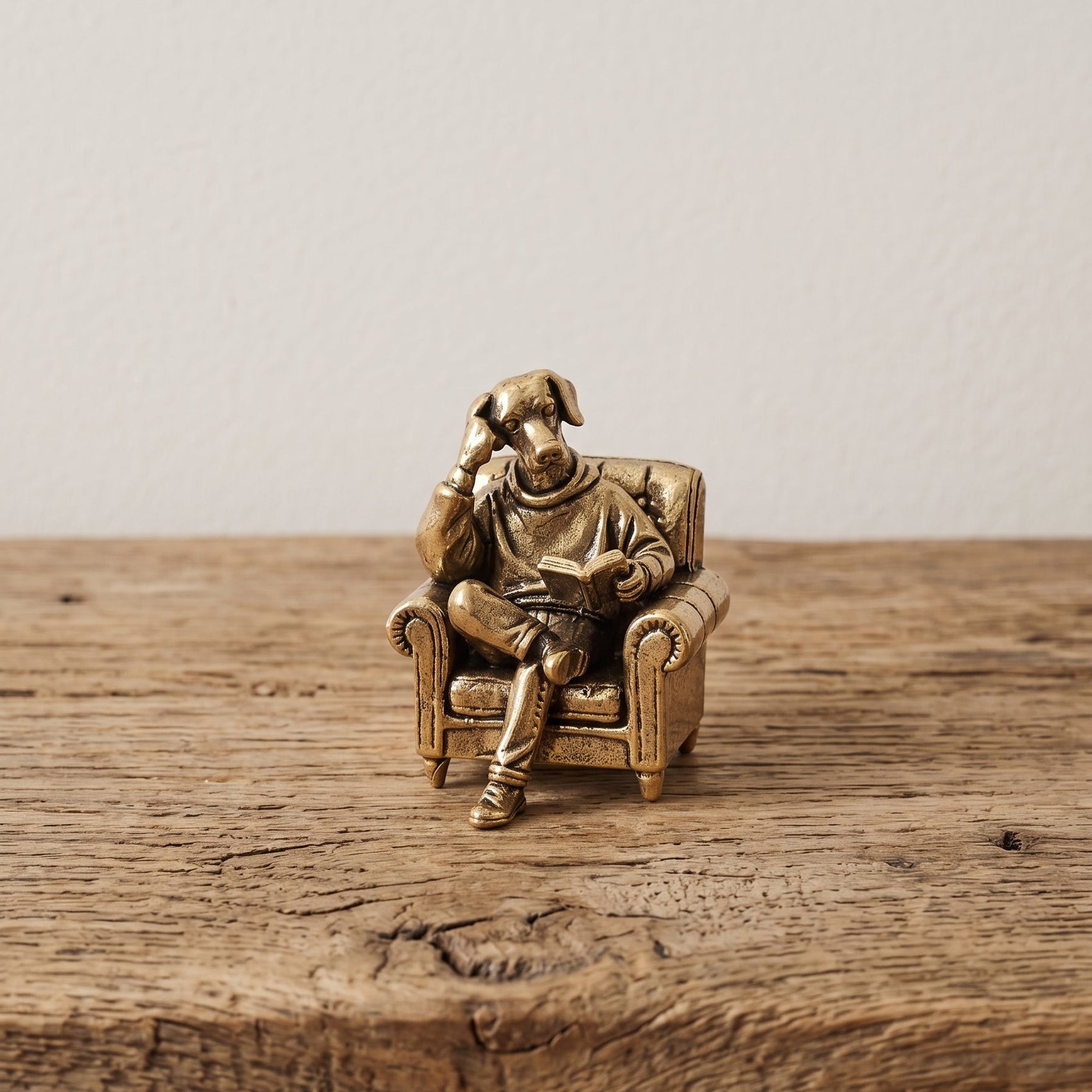 The Scholar miniature solid brass dog figurine reading a book in an armchair, with fine detail and aged antique patina