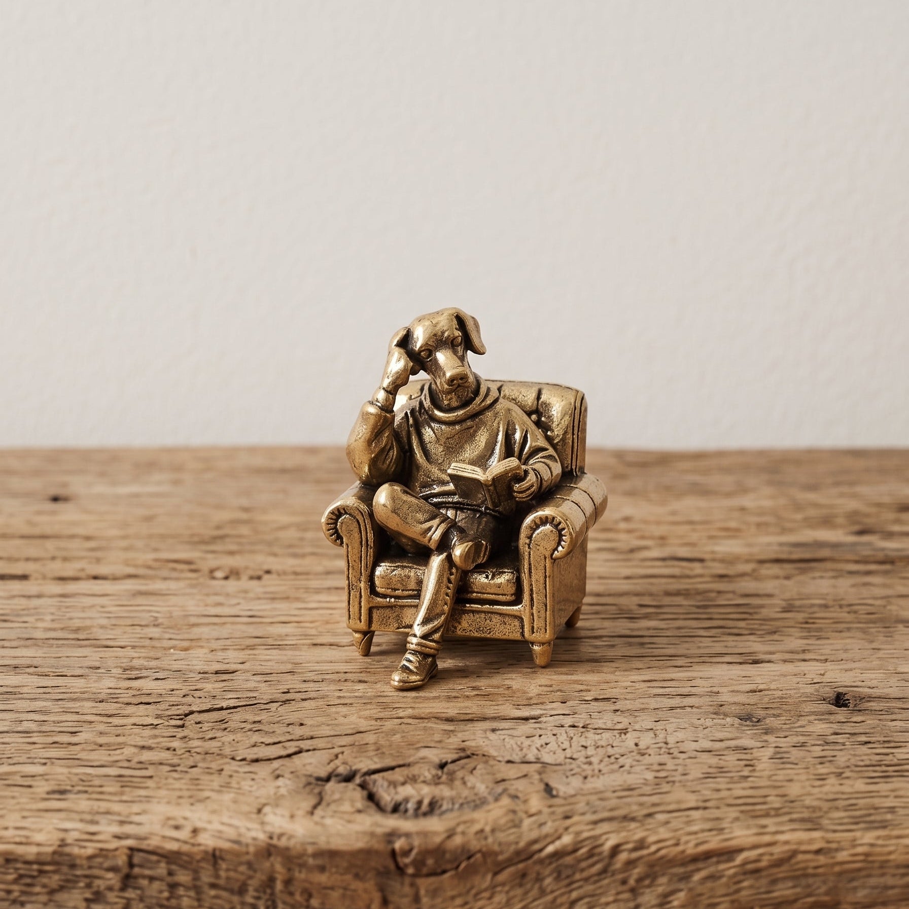 The Scholar miniature solid brass dog figurine reading a book in an armchair, with fine detail and aged antique patina