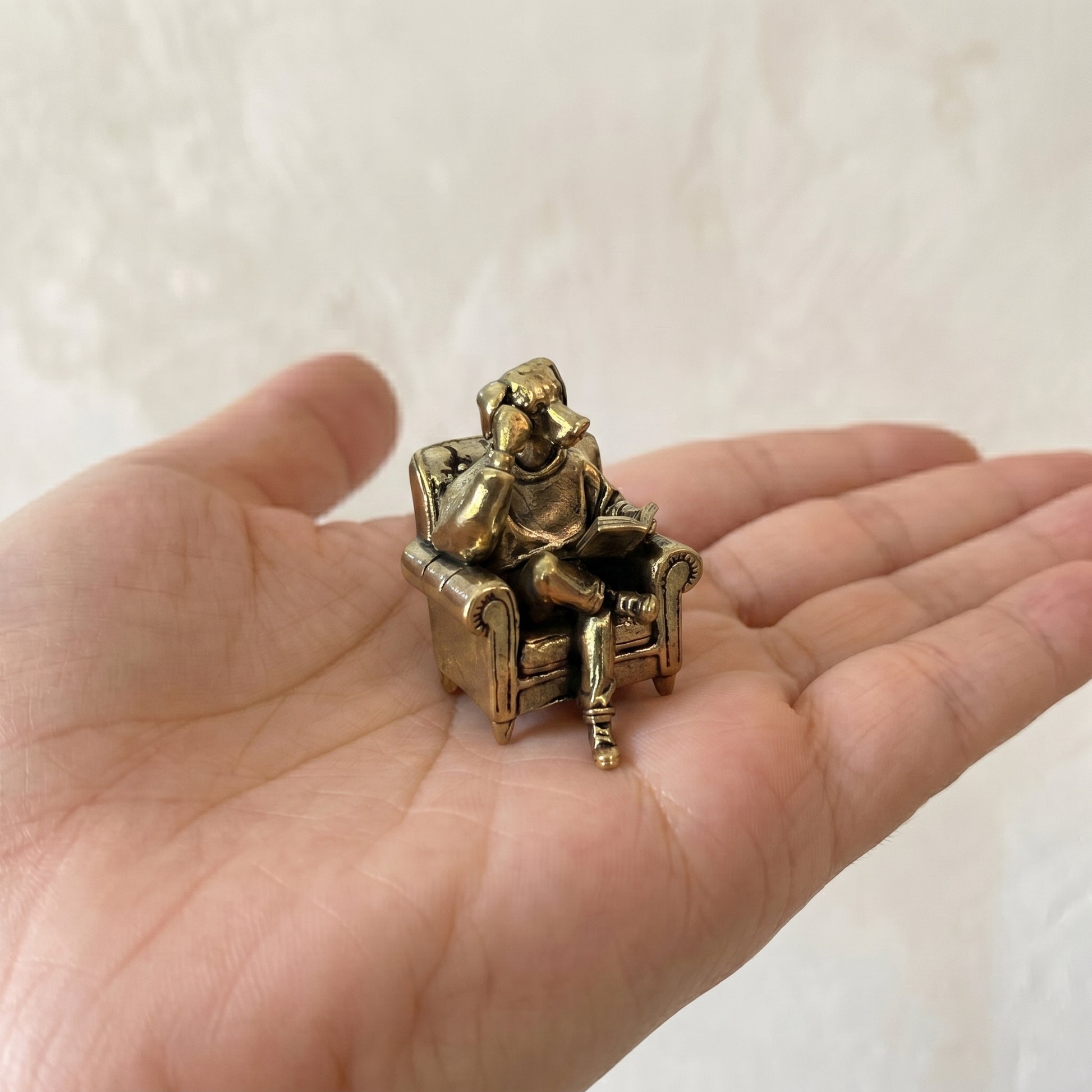 Three-quarter view of The Scholar brass reading dog showing the armchair and seated reading pose