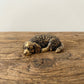 The Serene Soul miniature brass golden retriever held in hand to show scale, curled in a tight sleeping pose with golden patina