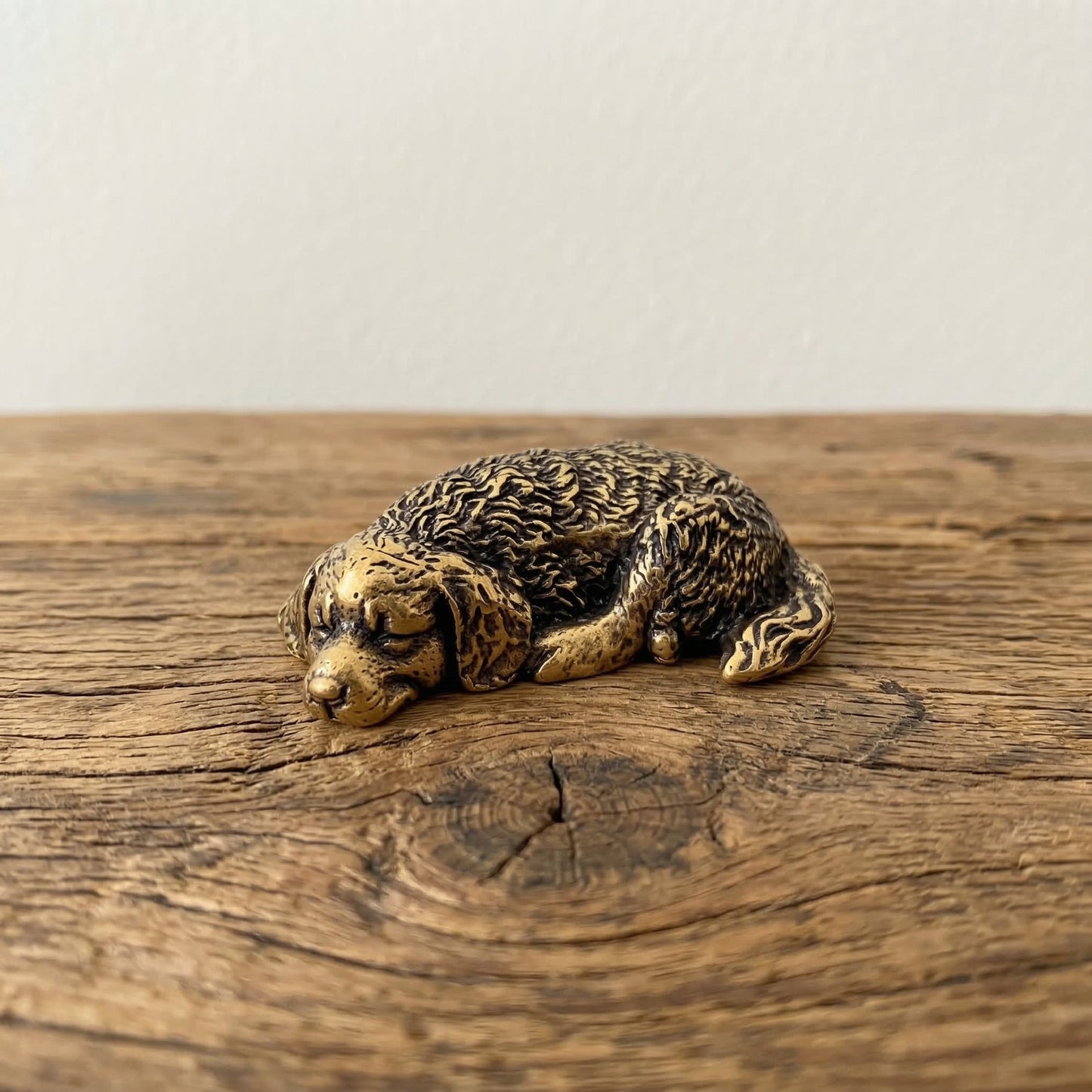 The Serene Soul miniature brass golden retriever held in hand to show scale, curled in a tight sleeping pose with golden patina