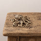 Overhead angle of a brass octopus figurine showing the sprawl of its eight arms and the cast suckers along each one