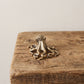 Solid brass octopus figurine with eight curling arms and a pebbled mantle, antique patina finish, resting on a weathered wood surface