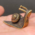 The Slow Path miniature solid brass snail figurine with a striped spiral shell and dotted texture, held in a hand