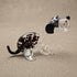 Front-angled view of The Spotted Sprinter lampworked glass dog figurine showing face detail with blue eyes, black nose, and purple-black spots in clear solid glass, by Glass by Iness
