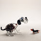 The Spotted Sprinter lampworked glass dog figurine with purple-black spots in clear glass alongside a miniature glass dachshund, handcrafted in L'viv Ukraine by Glass by Iness, from WILLAGE