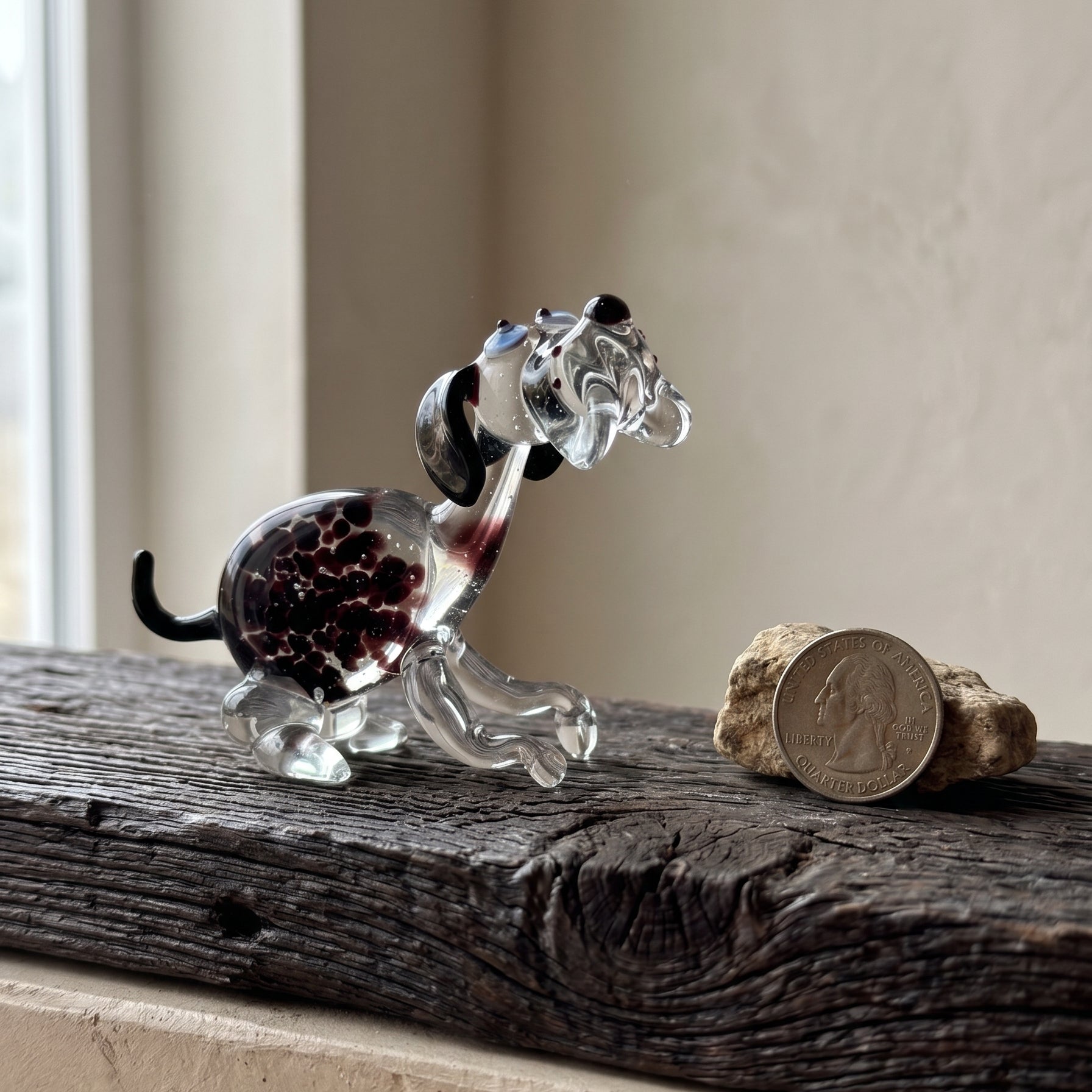Side view of The Spotted Sprinter lampworked glass dog showing purple-black spots suspended inside clear solid glass, handcrafted by Glass by Iness