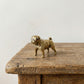 The Steadfast Companion miniature brass bulldog standing square on a wooden surface, showing stocky build and warm aged patina, from the WILLAGE Tiny Objects collection