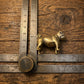 The Steadfast Companion miniature brass bulldog shown with ruler for scale, approximately 40 mm long, on a wooden surface