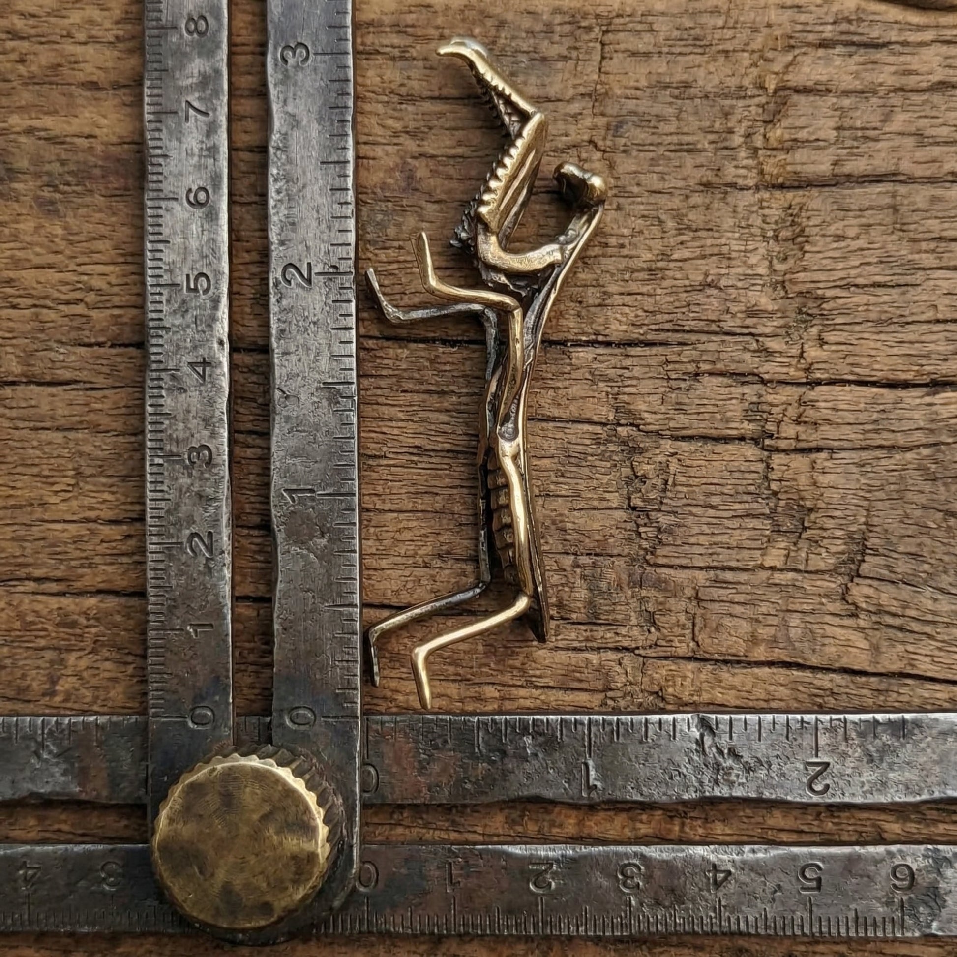 The Still Hunter miniature brass praying mantis held in hand to show scale, with detailed legs and golden patina