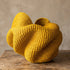 Front view of a yellow Bolga basket showing its wide, petal-like folded opening and fine coiled weave