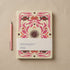 2027 weekly diary with a butter-yellow textured cover printed in magenta, rust and brown folk-art florals around a central dark sun, shown with its paper belly band