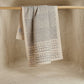 The Pattern hand block printed kora cotton kitchen towel in natural and slate grey hanging on wooden rod