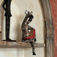 and-carved thinking zebra wood sculpture perched on decorative shelf showing 3-inch sitting notch and dangling leg