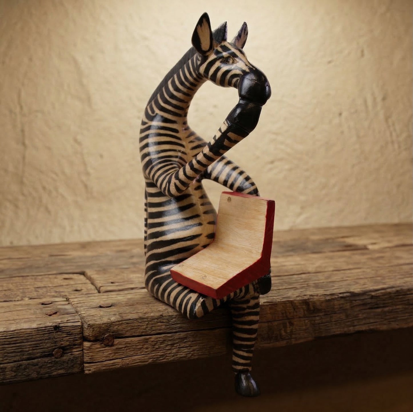 The Thinking Zebra hand-carved wood shelf sitter sculpture reading a red book with hand-painted black and white stripes
