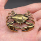 The Tide Keeper brass crab held in a hand to show its small size, solid brass with warm patina
