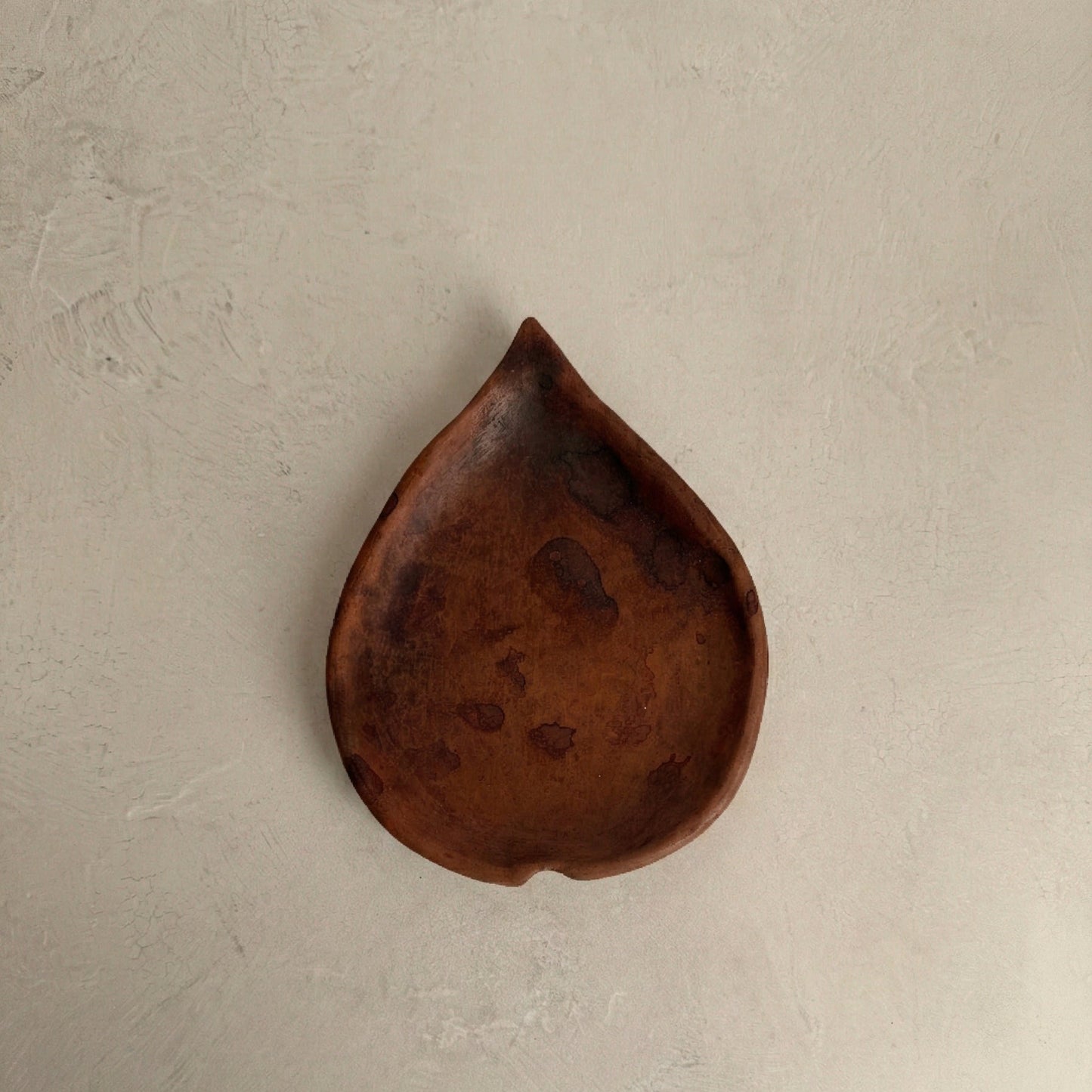 Tympew betel leaf plate in handcrafted black clay showing organic leaf-shaped form and burnished surface, Lyrnai pottery from Meghalaya India, from WILLAGE