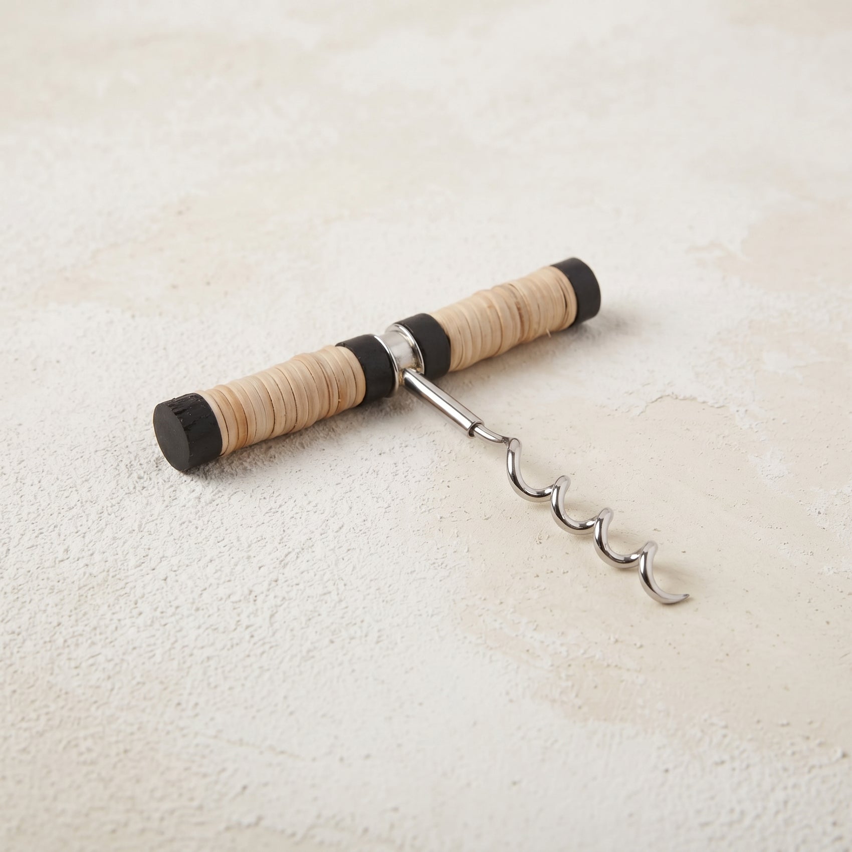 Pull-style corkscrew with a black mango wood and natural rattan wrapped handle and a stainless steel worm
