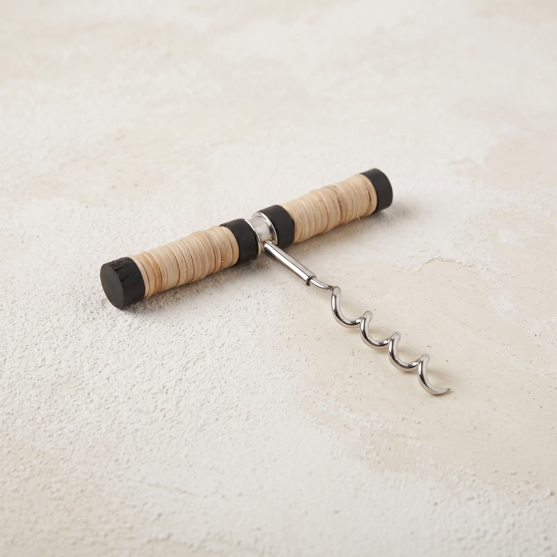 Pull-style corkscrew with a black mango wood and natural rattan wrapped handle and a stainless steel worm
