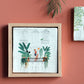 Urban Jungle Storytile framed and displayed on a warm-toned wall showing illustrated balcony garden, hand-baked ceramic by Marga van Oers in the Netherlands, from WILLAGE