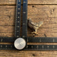 The Vigilant Nurturer miniature brass hen shown with ruler for scale, approximately 39 mm tall, with detailed feathers and aged patina on a wooden surface