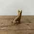 The Vigilant Protector miniature brass German Shepherd in alert standing pose, showing muscular detail and warm aged patina on a wooden surface, from the WILLAGE Tiny Objects collection