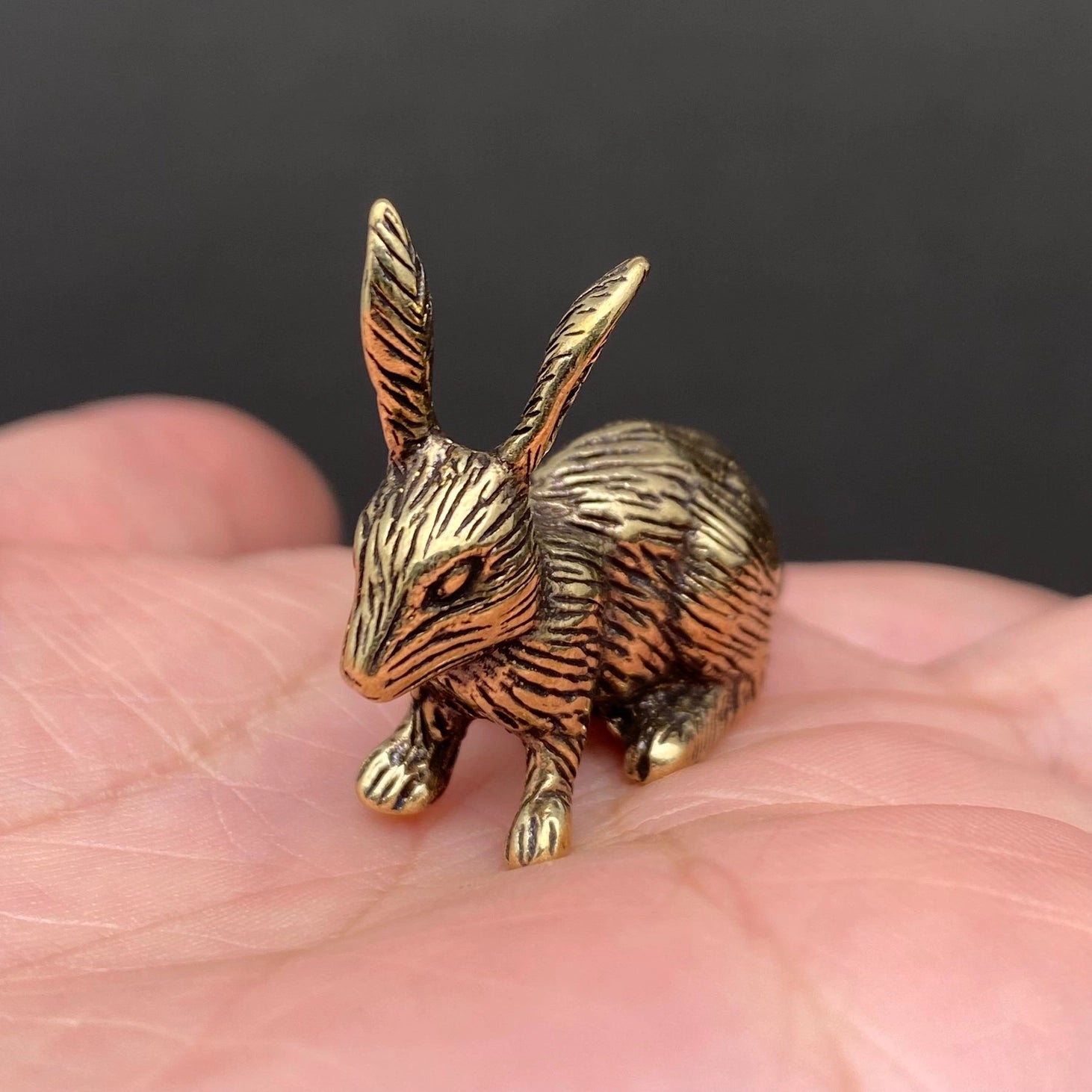 The Vigilant Seeker miniature brass rabbit held in hand to show scale, with upright ears and warm aged patina, from the WILLAGE Tiny Objects collection

