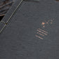 Close-up of copper foil letterpress constellation and Walt Whitman quote on charcoal handmade paper journal cover