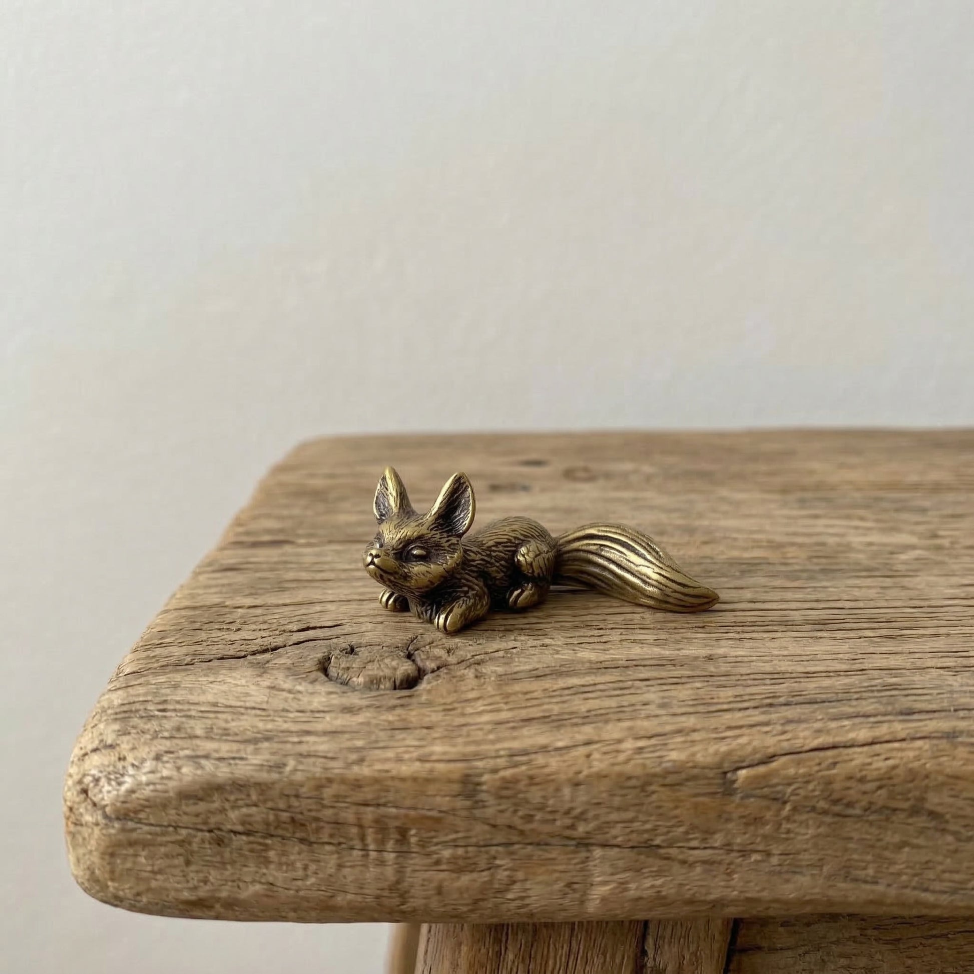 The Watchful Spirit miniature brass fox held in hand to show scale, with detailed fur and curled tail
