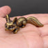 The Watchful Spirit miniature brass fox in a seated alert pose on a wooden surface, with warm aged patina, from the WILLAGE Tiny Objects collection
