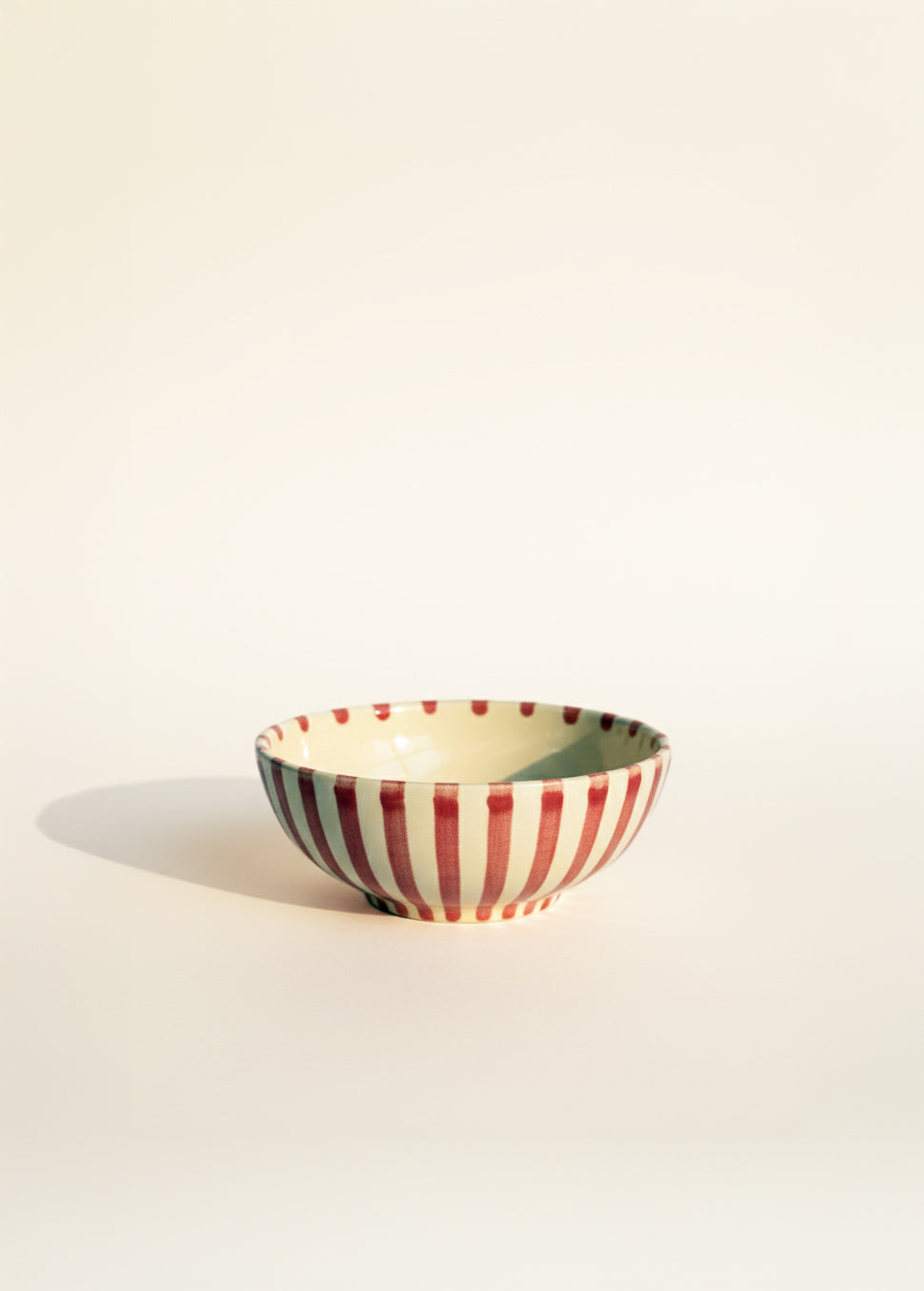 Ceramic bowl with red and white striped pattern on a beige background