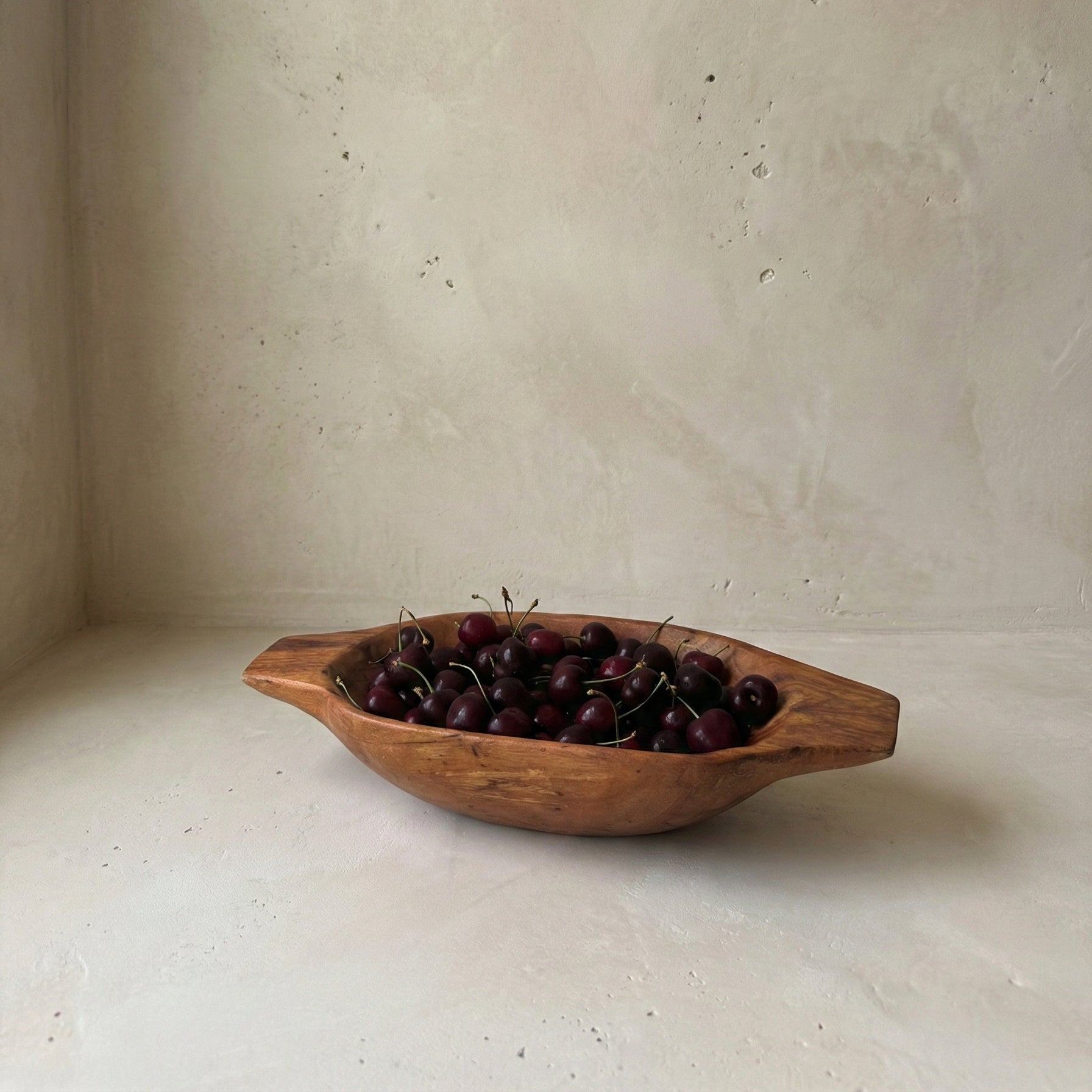 Wooden bowl with cherries on a light background