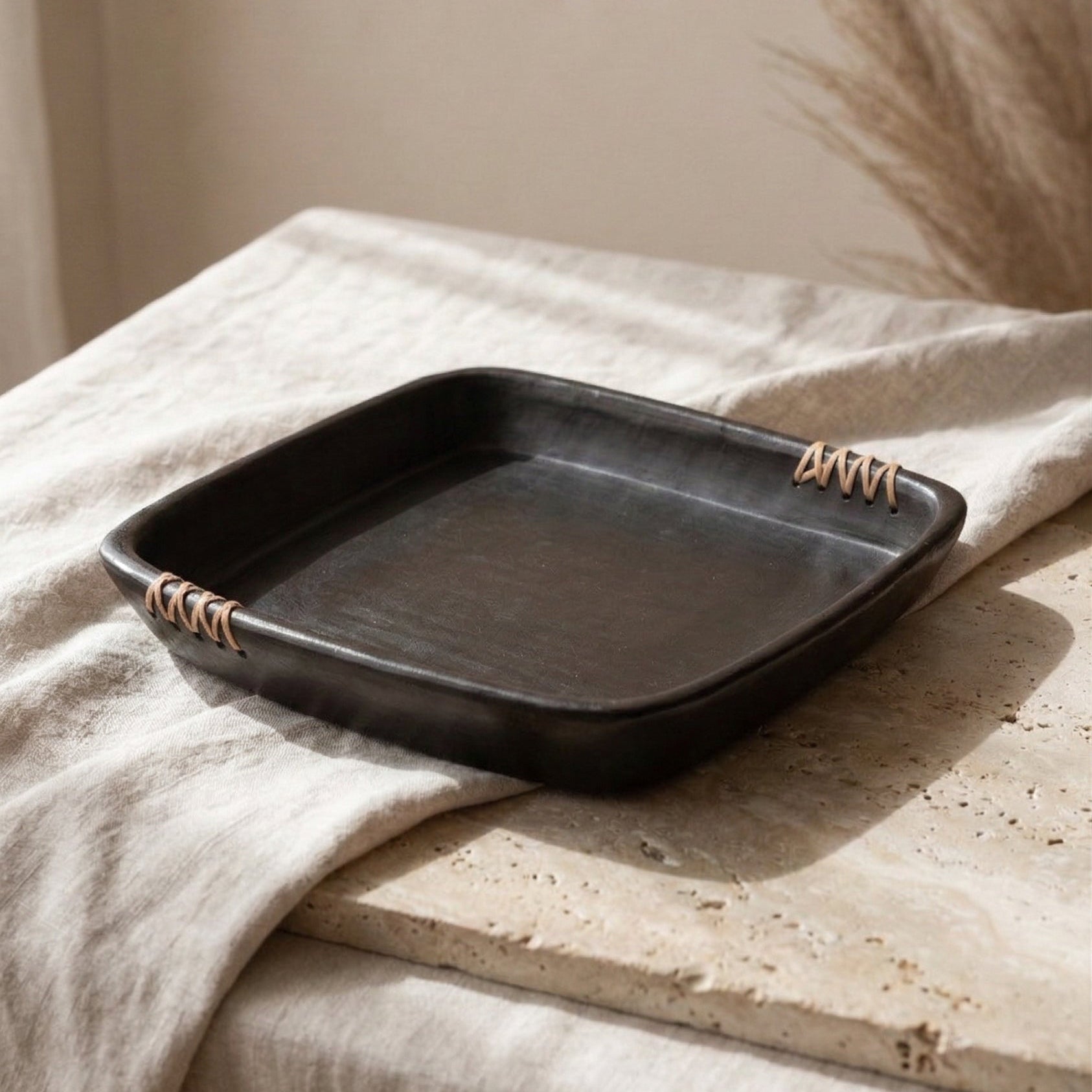 Black rectangular tray with handles on a beige surface