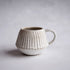Ceramic mug with textured design on a plain background