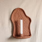 clay wall-mounted candle holder with a white candle on a beige background