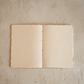 Open beige notebook on a textured beige surface