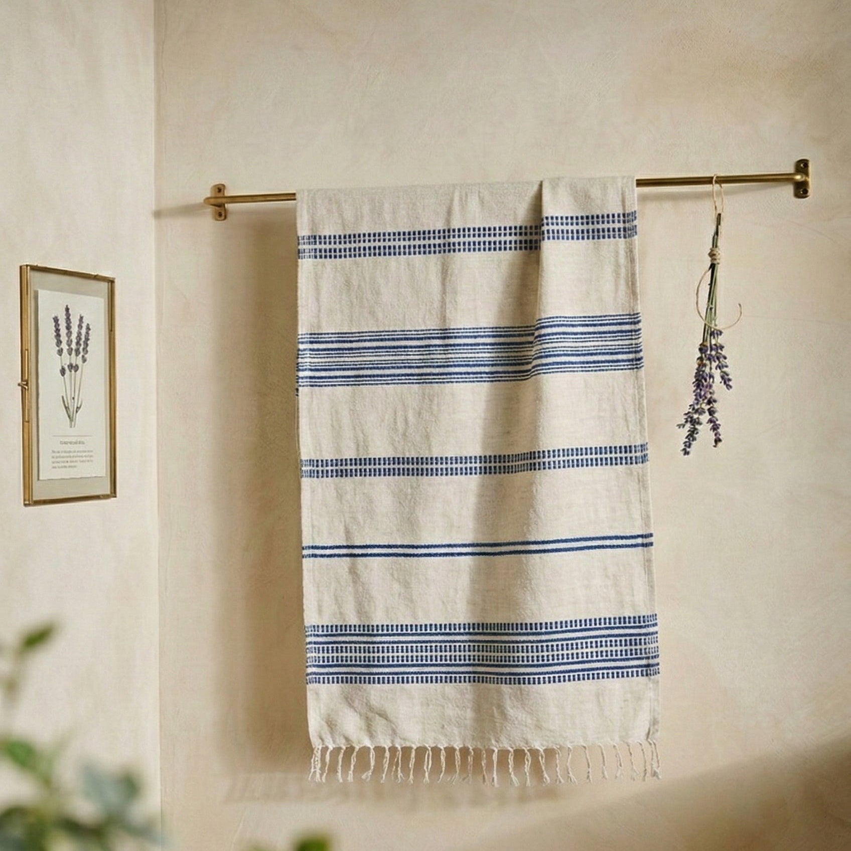 Striped towel hanging on a rack with a wooden bench and plant in the foreground.