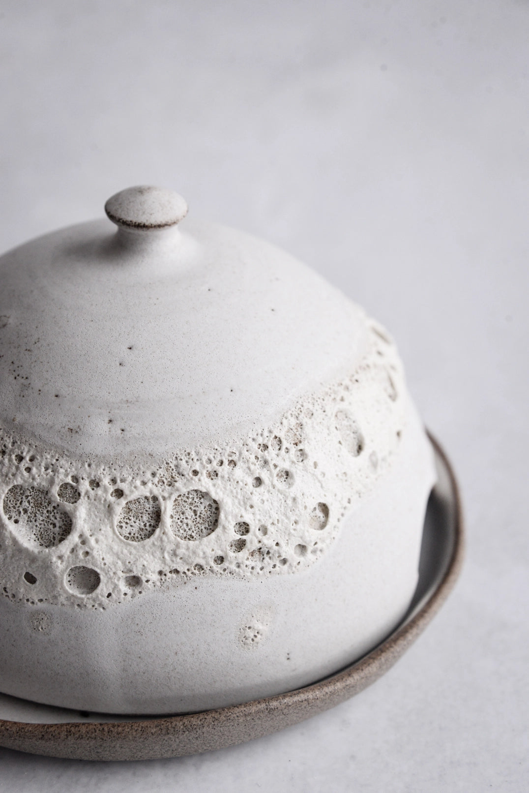 Small ceramic dish for butter or cheese, handmade with crater texture.