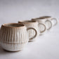 Neutral-toned artisan mug with ribbed detail, ceramic pottery