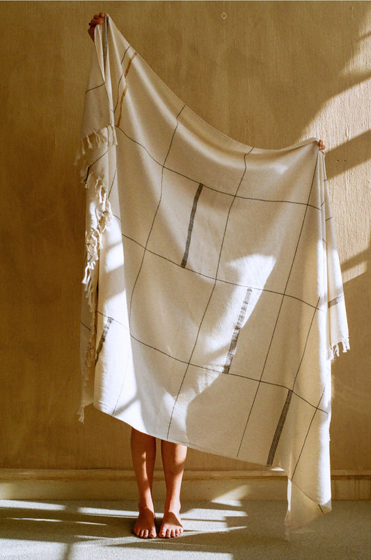 Neutral-toned artisan throw with fringe, inspired by yogic design