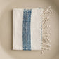 Folded towel with blue pattern and white fringes on a beige background