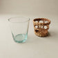 Clear glass tumbler and woven basket on a neutral background