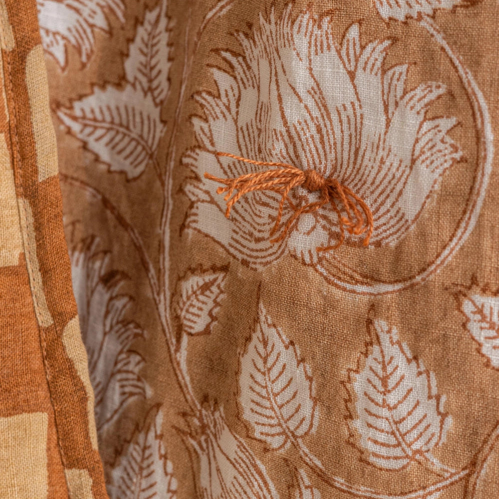 Marigold hand-block printed linen quilt in white botanical leaf pattern on terracotta ground, US King size, draped to show full design, from WILLAGE