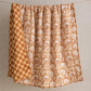 Detail of reversible side of Marigold linen quilt showing hand-block printed checkerboard pattern in terracotta and natural tones